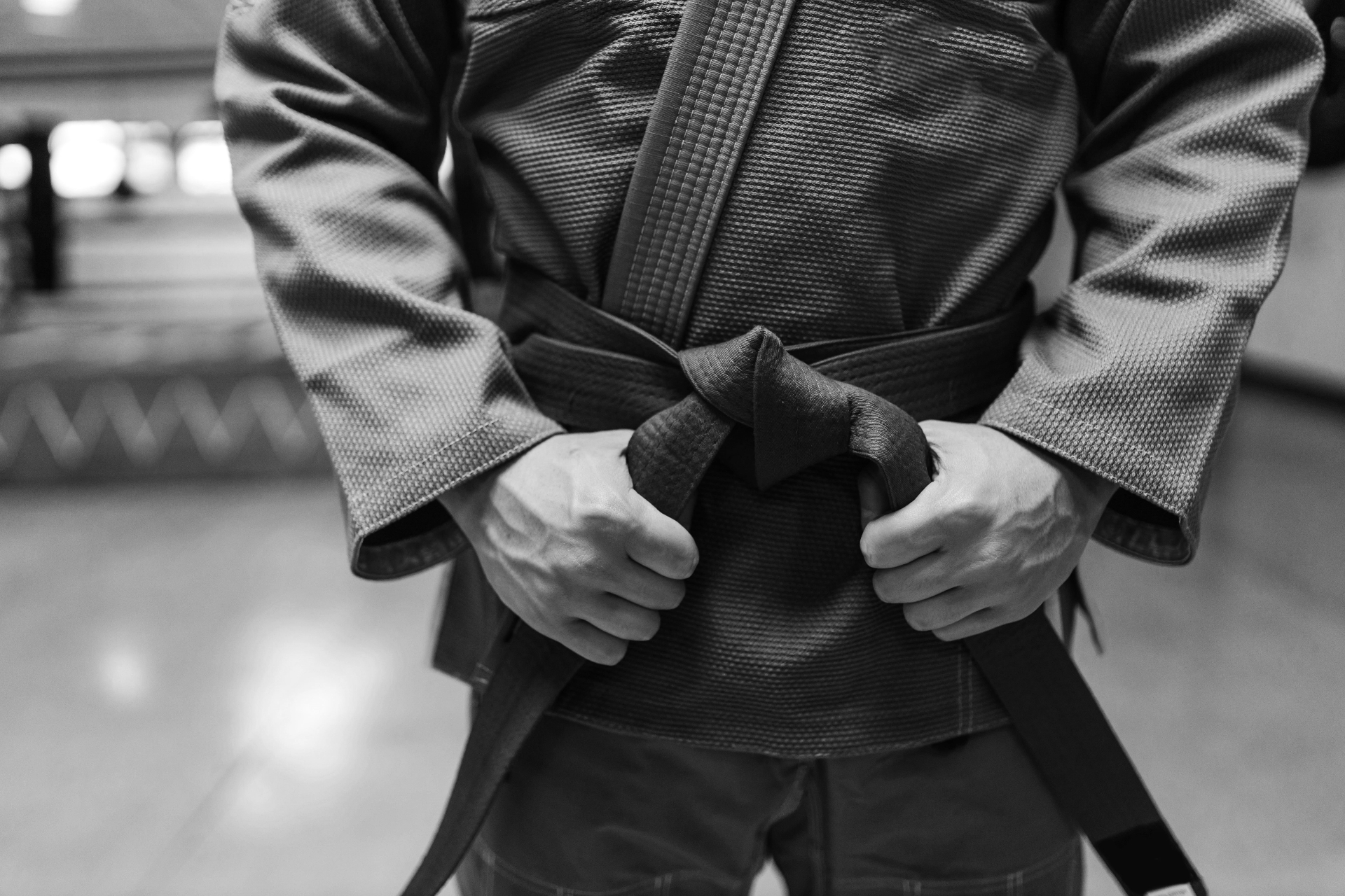 Practitioner tying a black belt on tatami